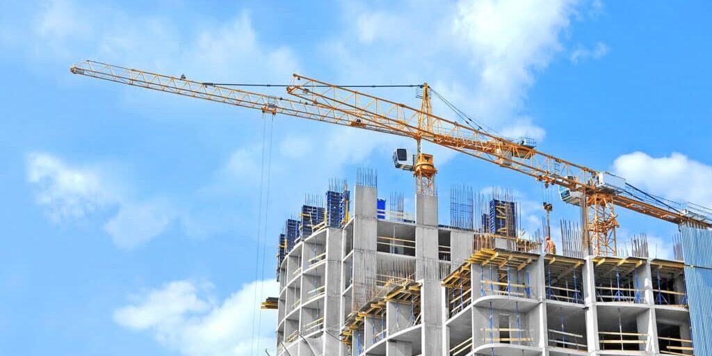 Crane and building construction site against blue sky